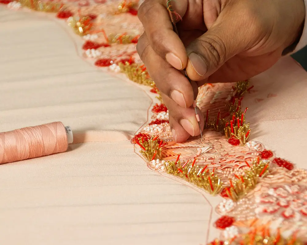 A craftsman at Mrunal Khimji sewing an intricate design on clothing